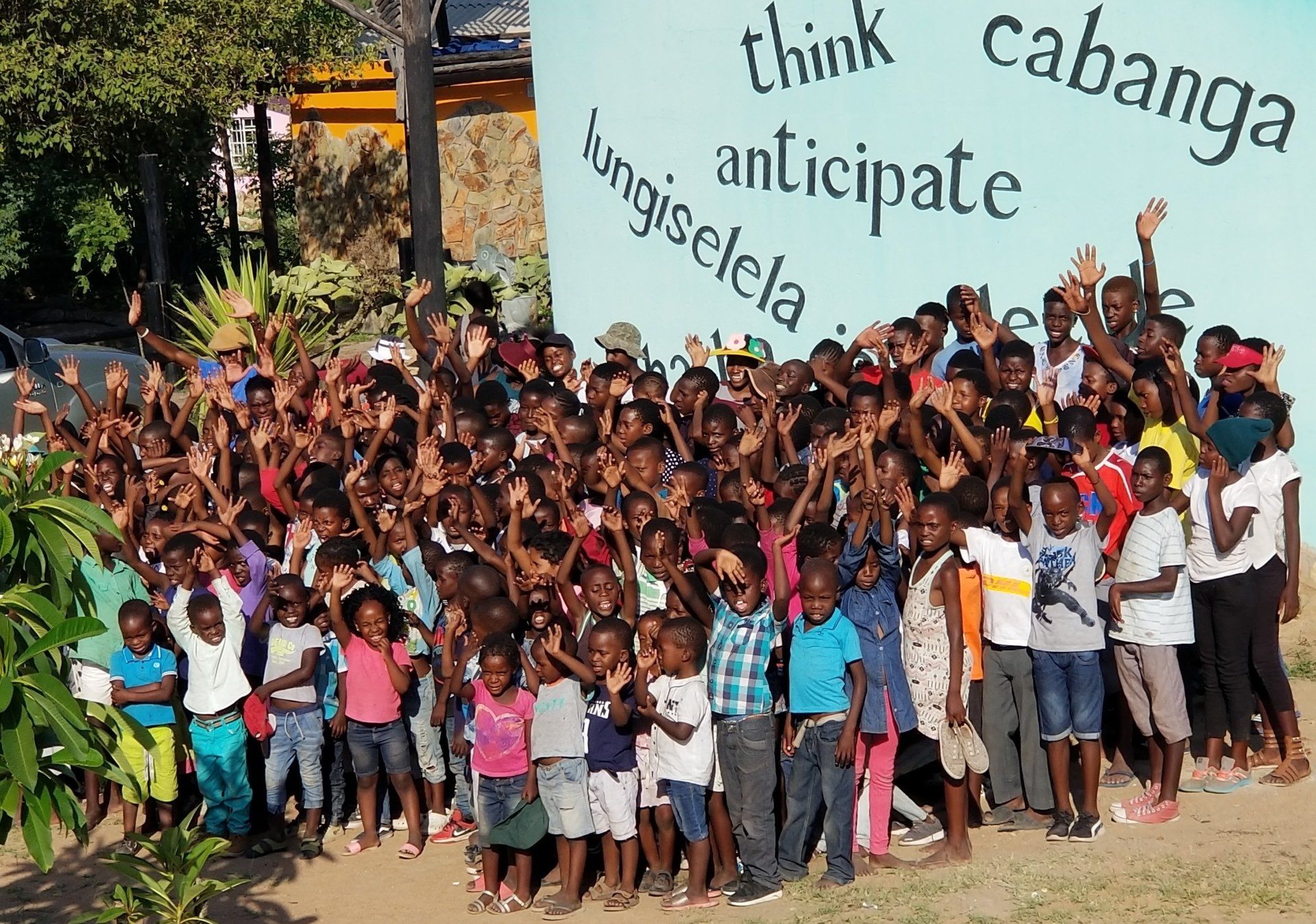 A large group of children standing in front of a sign that says think cabanga