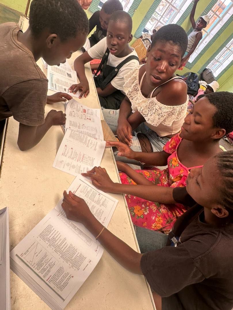 A group of children are sitting around a table writing on papers.