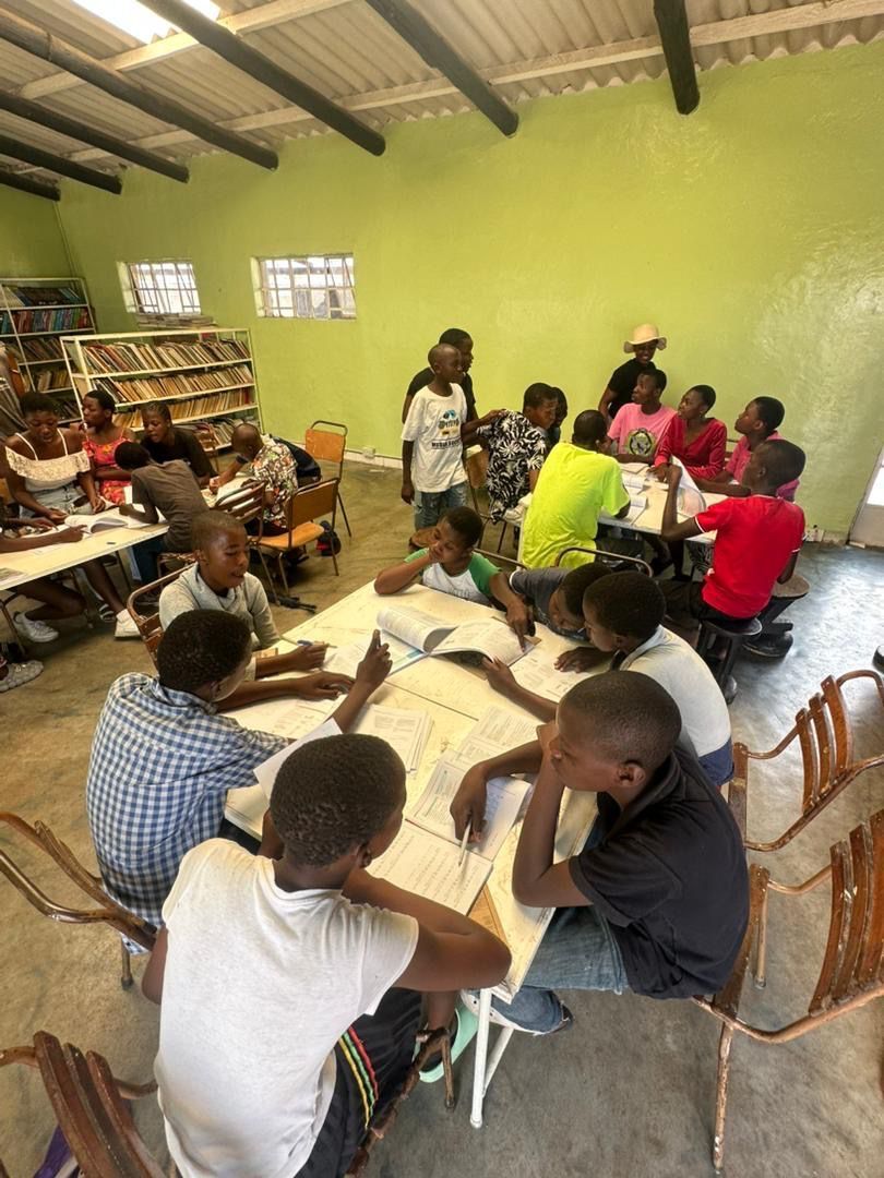 A group of children are sitting around a table in a room.