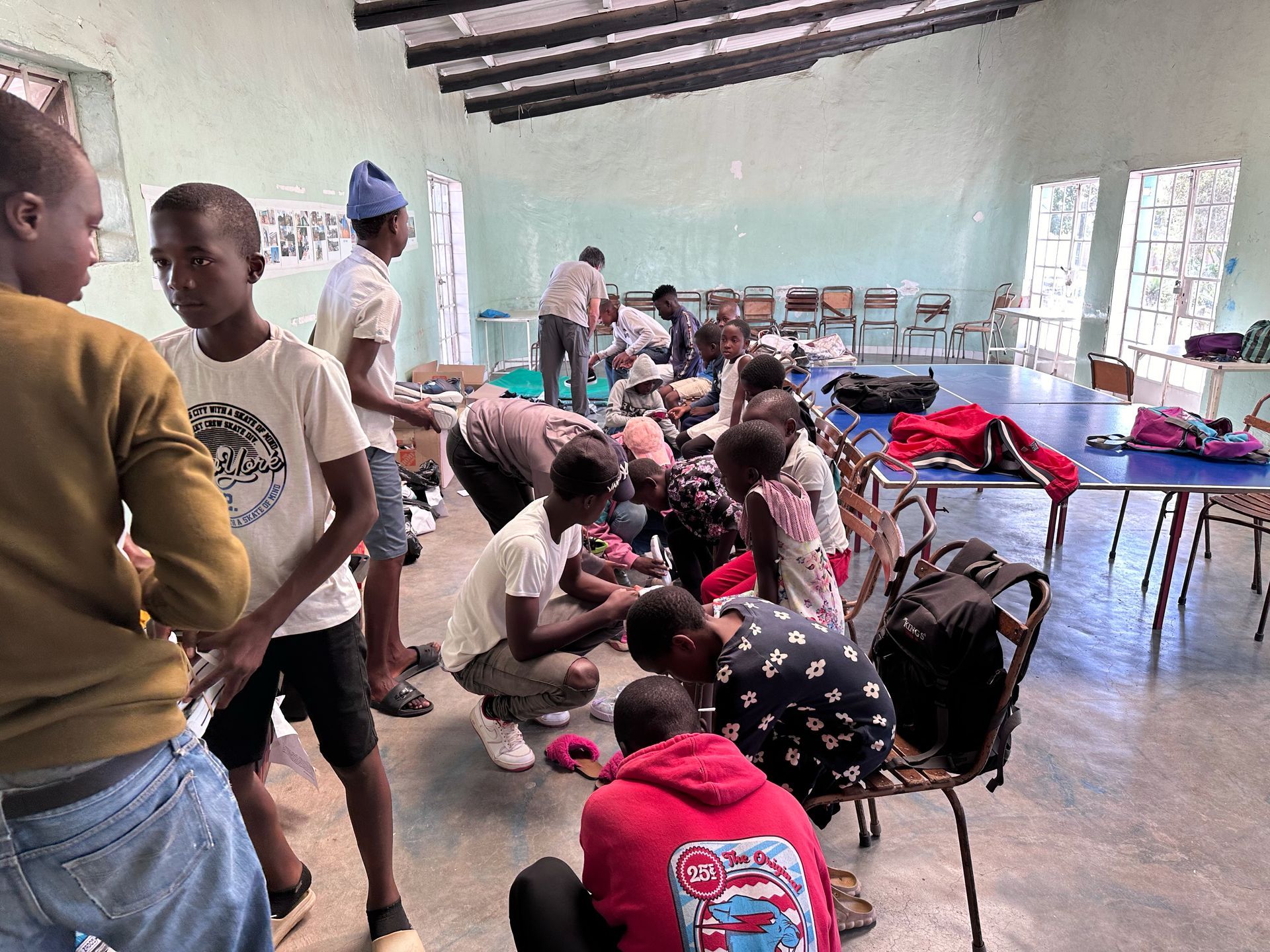 A group of children are playing in a room with tables and chairs.