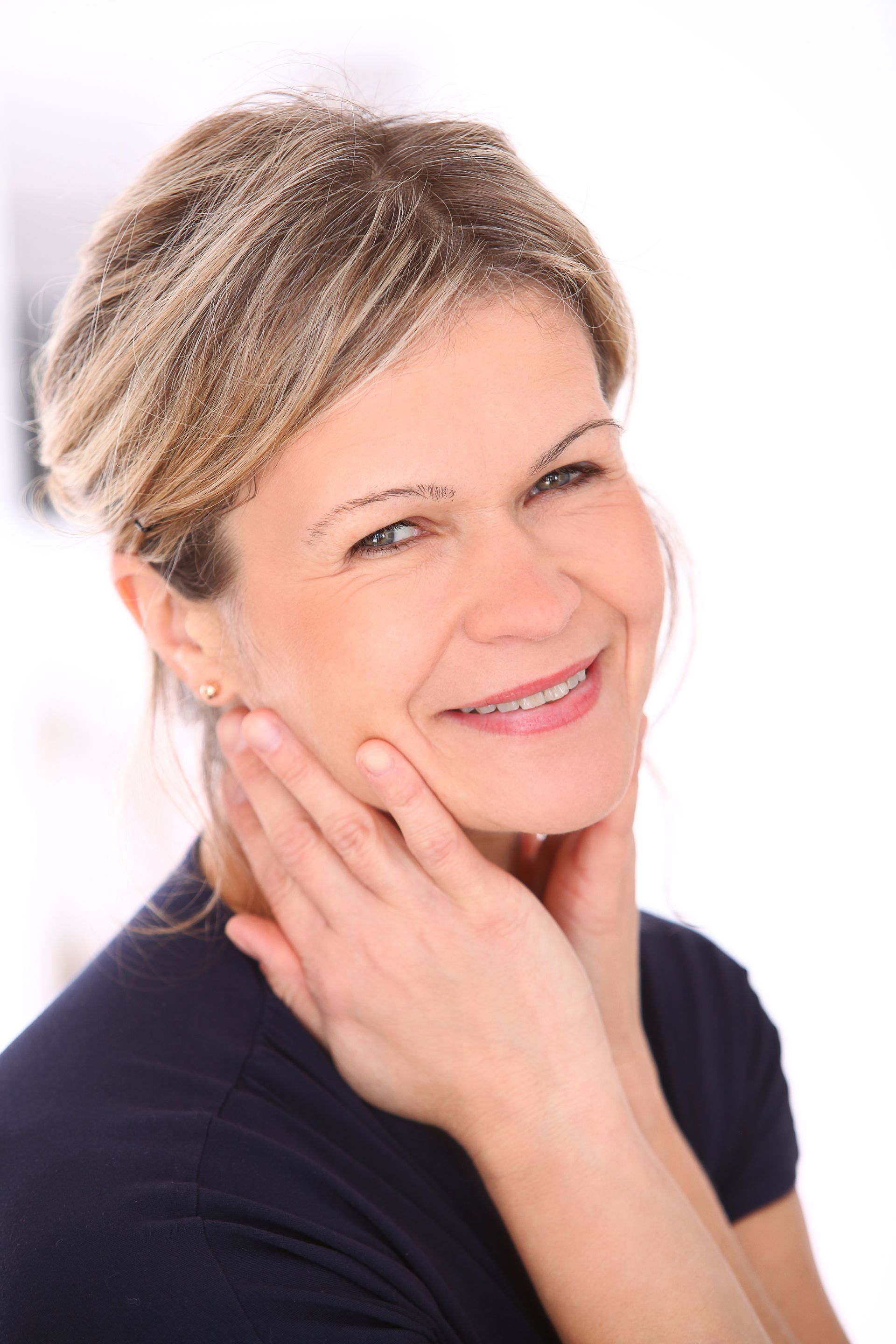 a woman is smiling and touching her face with her hand