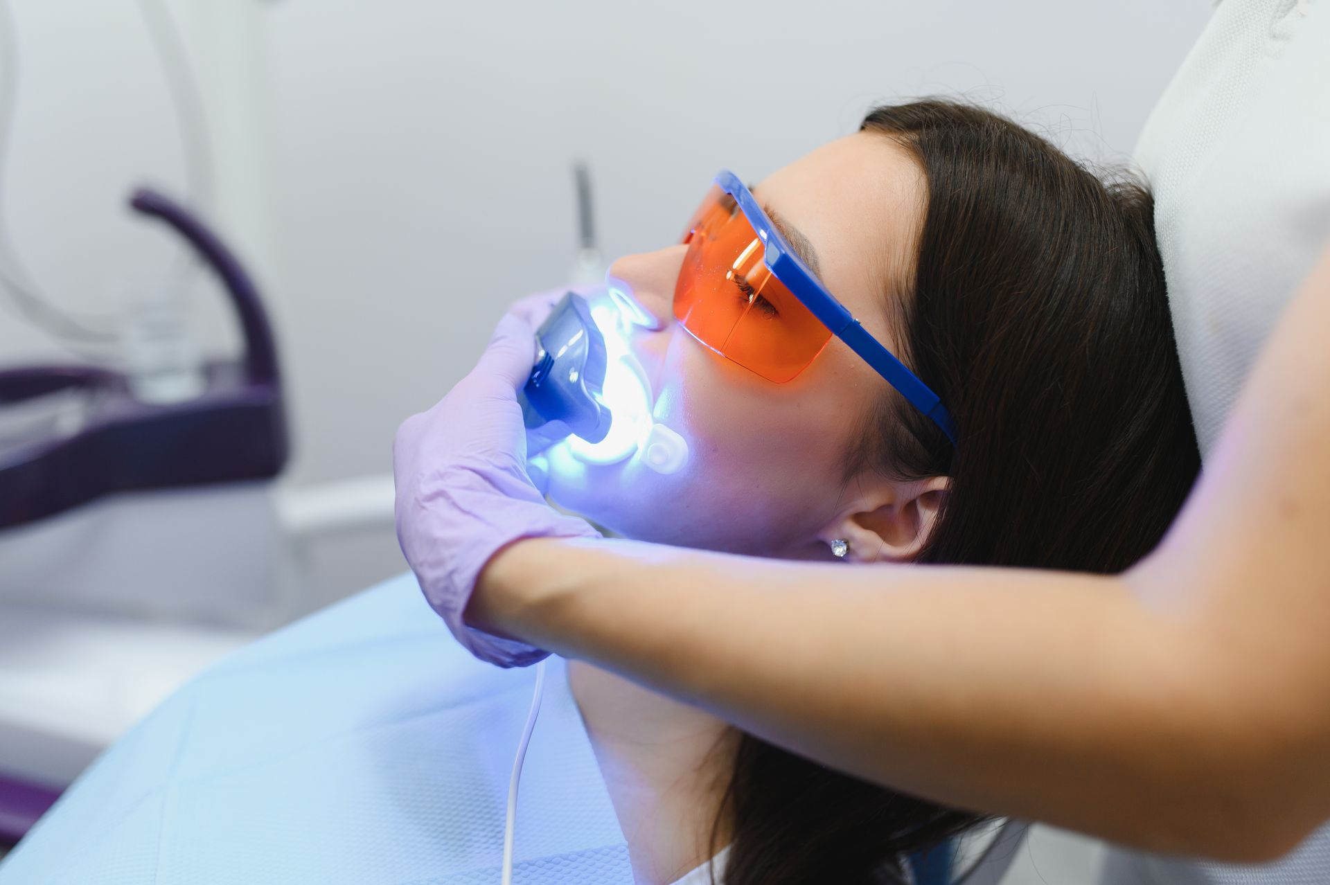 a woman is getting her teeth whitened by a dentist .