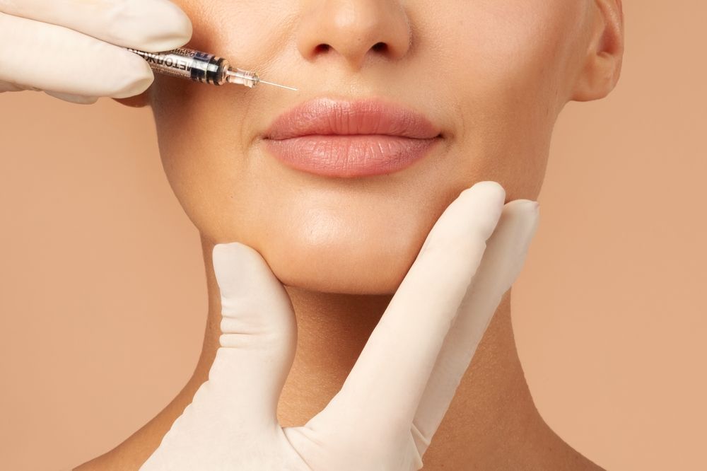 A woman is getting a botox injection in her lips.