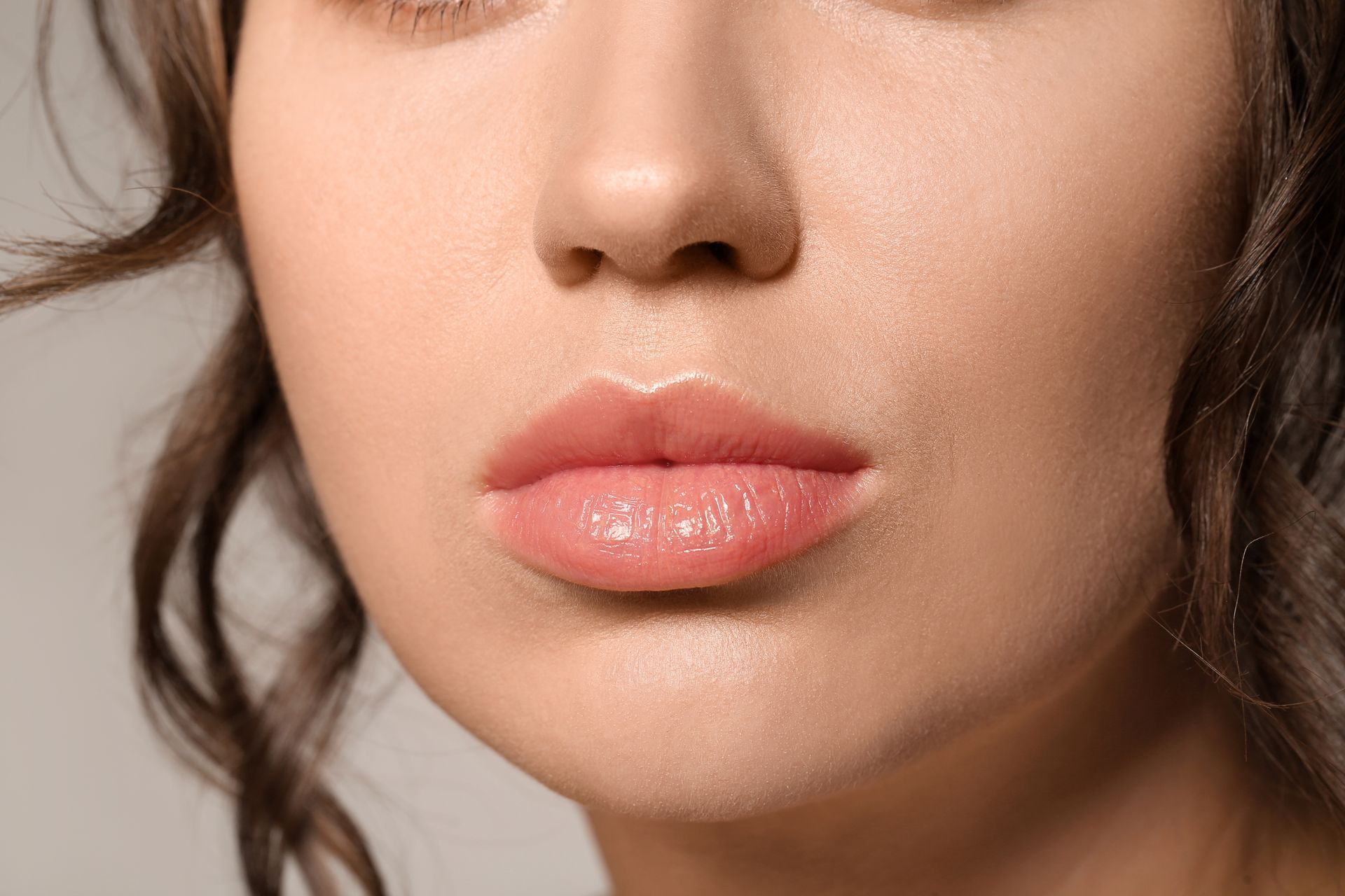 A close up of a woman 's lips and nose on a gray background.