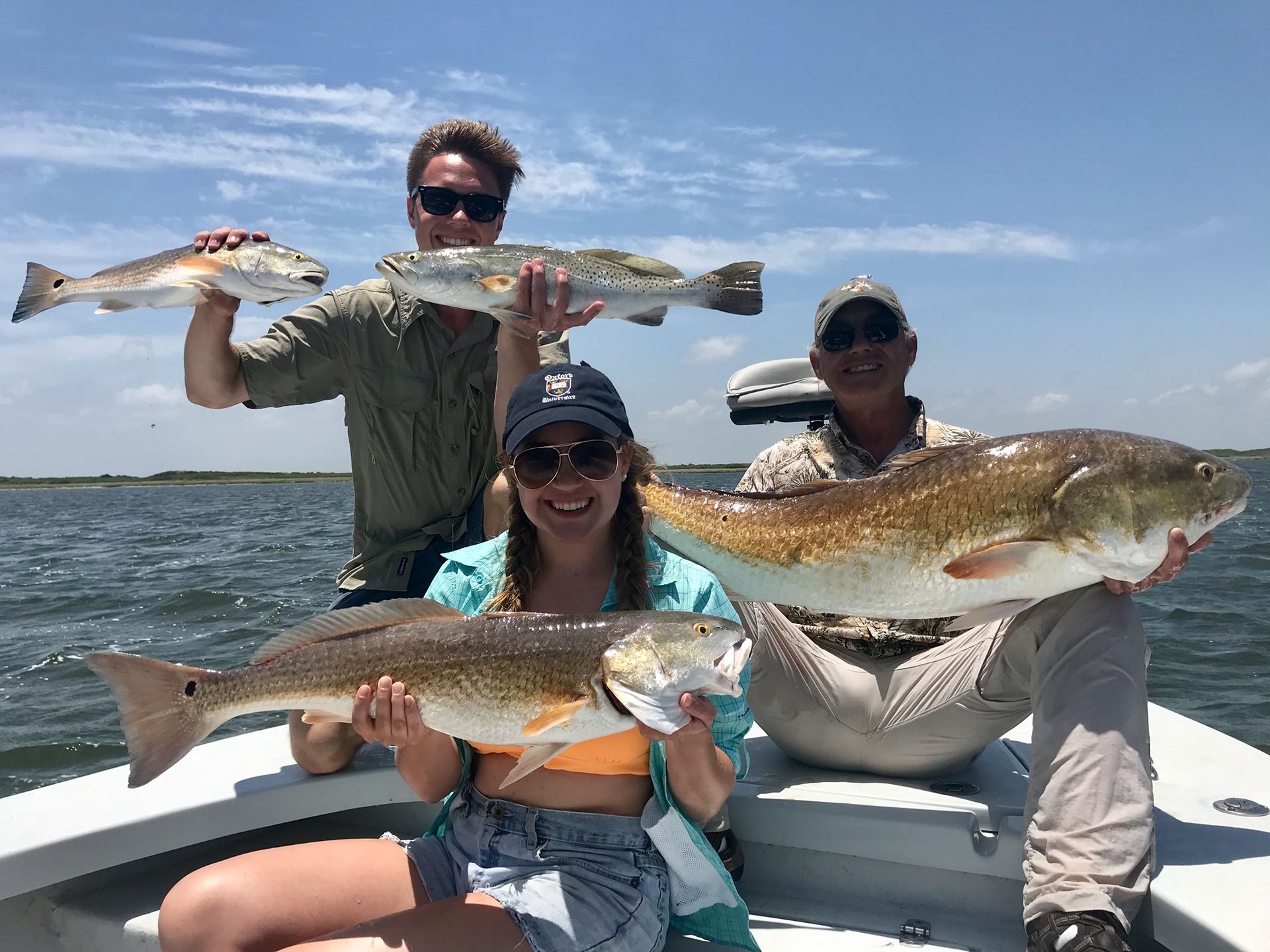 A group of people are sitting on a boat holding fish.