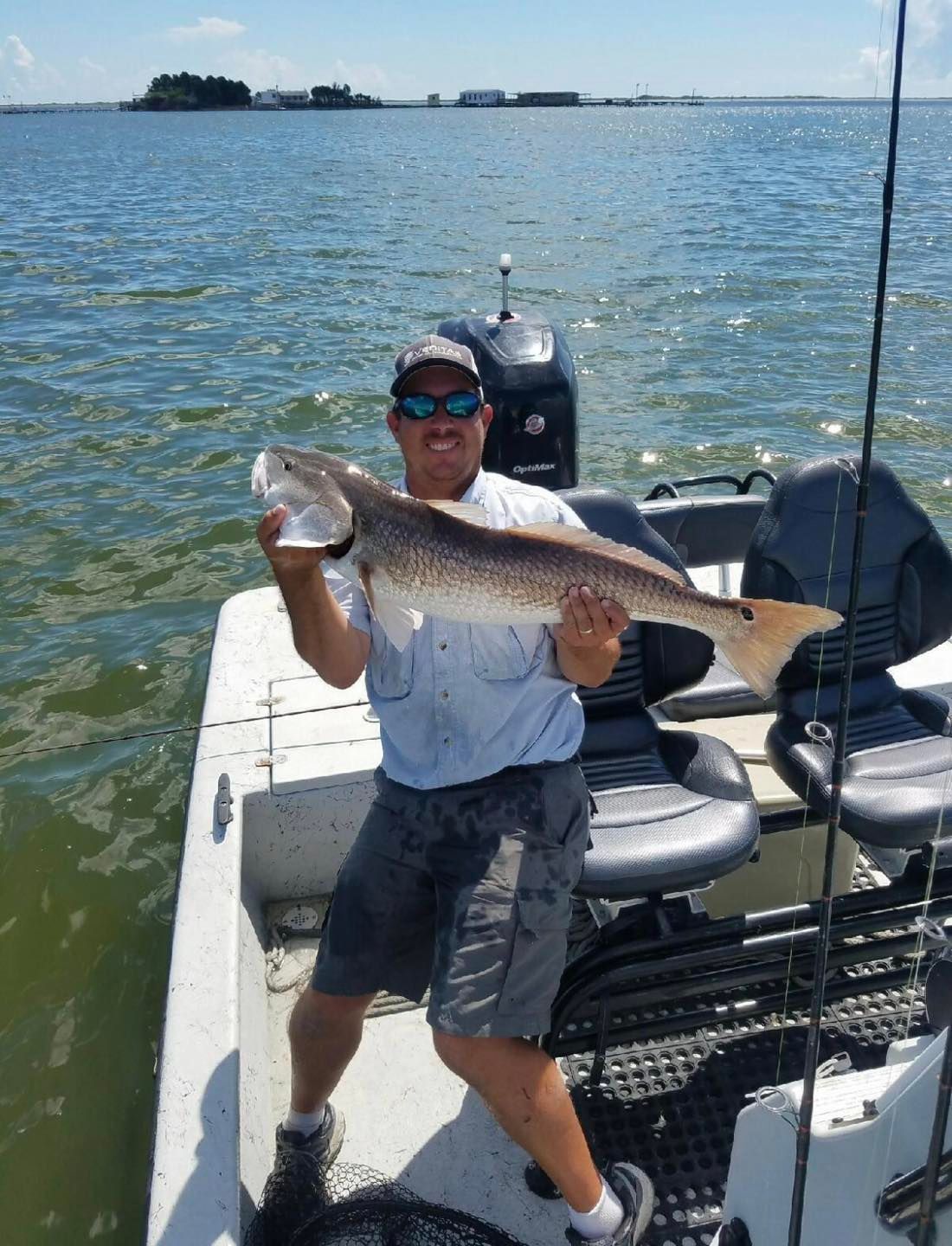 A man is standing on a boat holding a large fish.