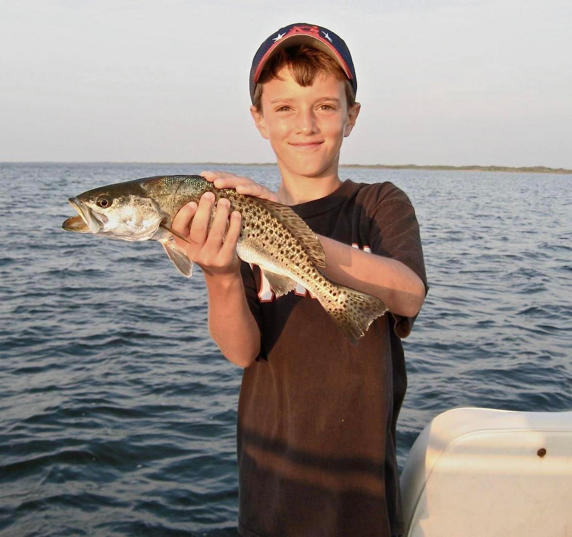 A young boy is holding a large fish in his hands