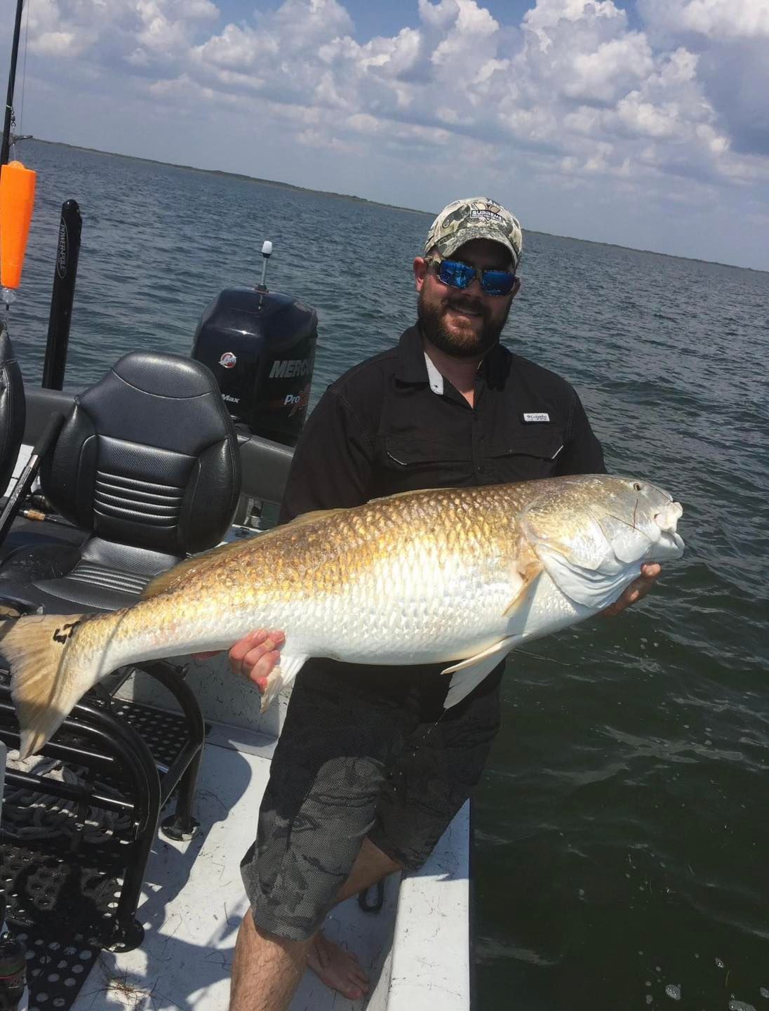 A man is holding a large fish on a boat.