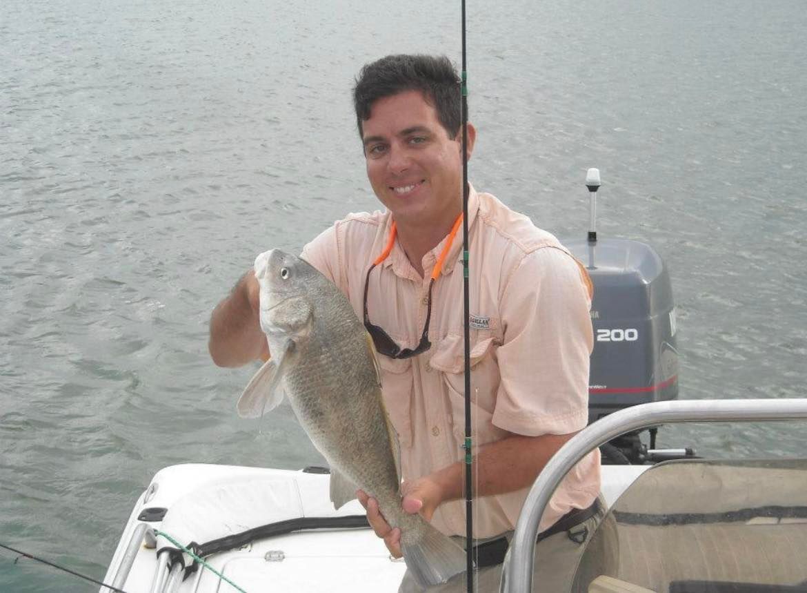 A man on a boat holding a large fish