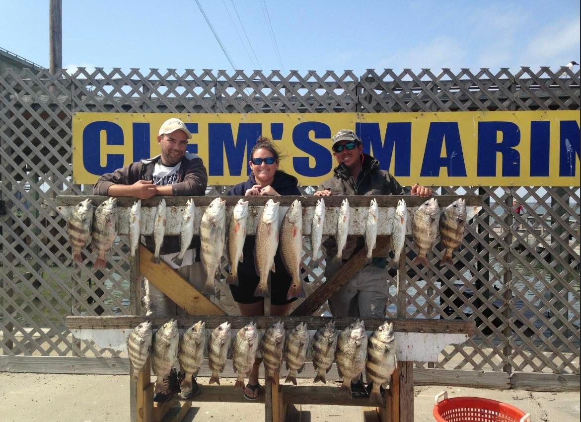 A group of people standing in front of a sign that says clem 's marine