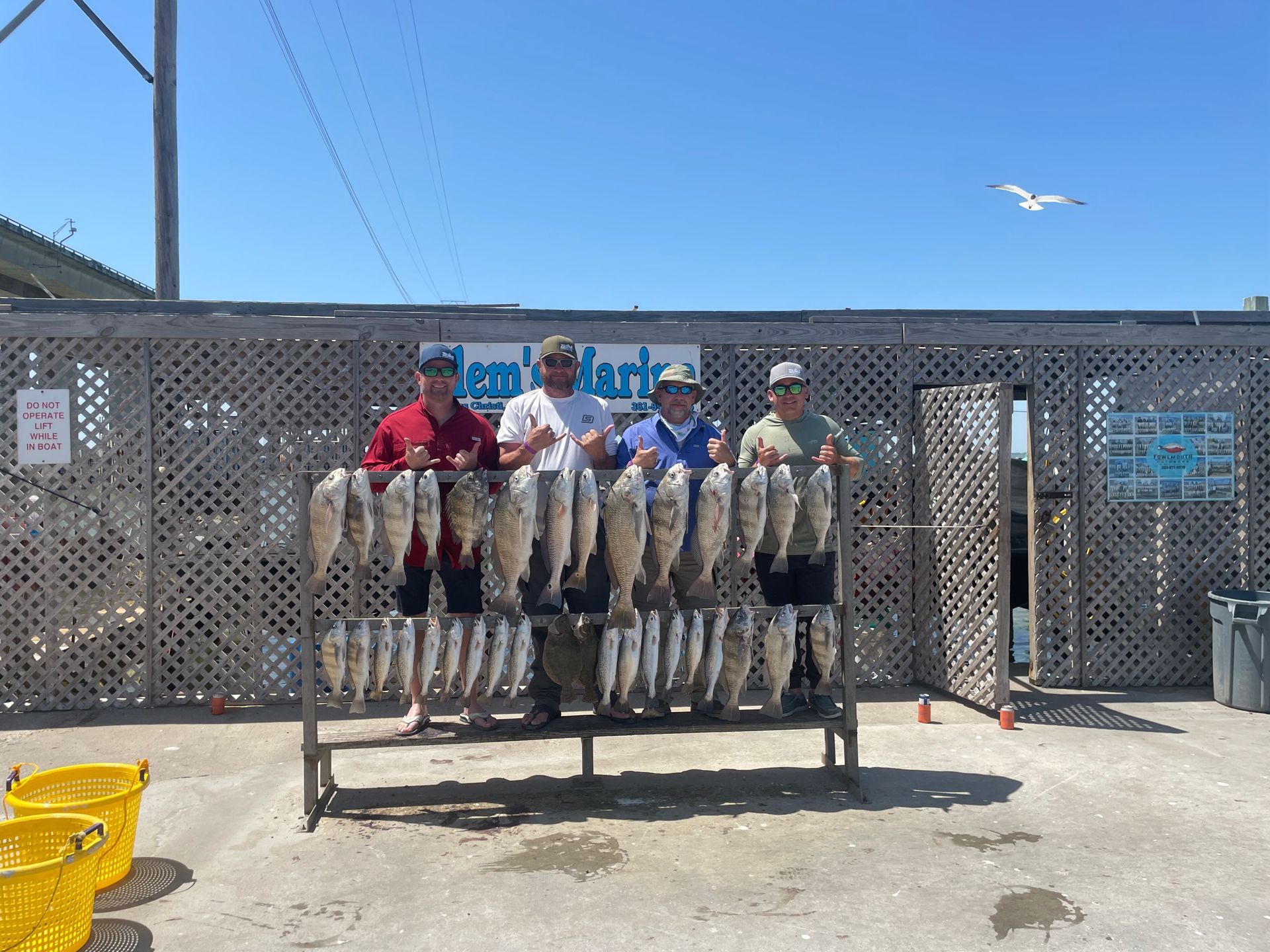 A group of men standing next to a rack of fish.