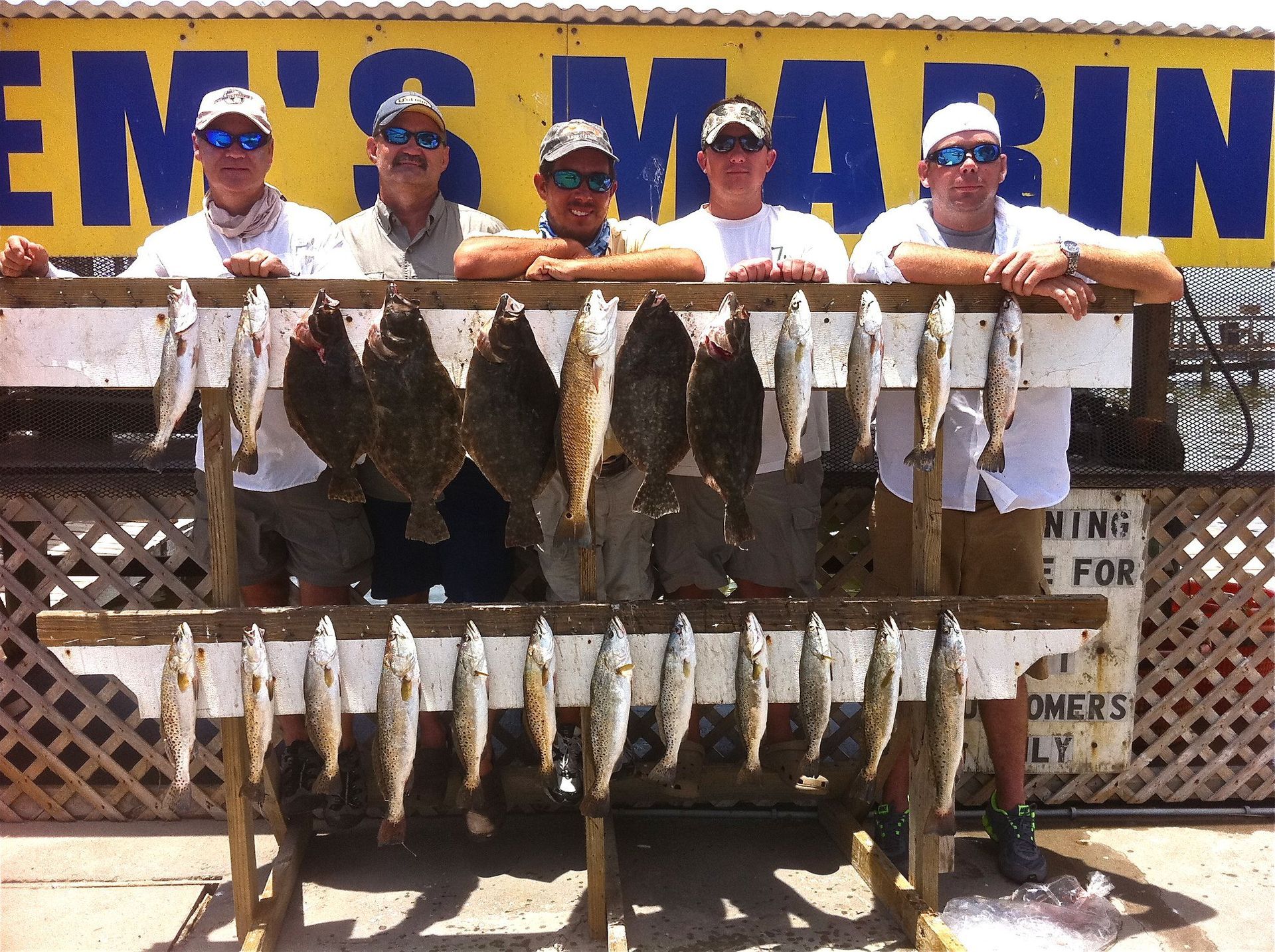 A group of men standing in front of a sign that says em 's marina
