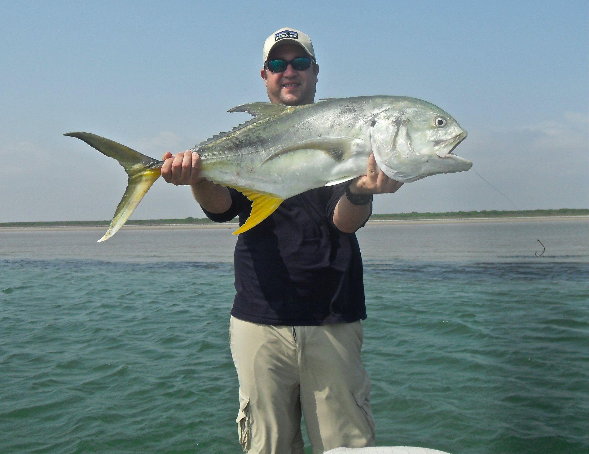 A man is holding a large fish in his hands in the water