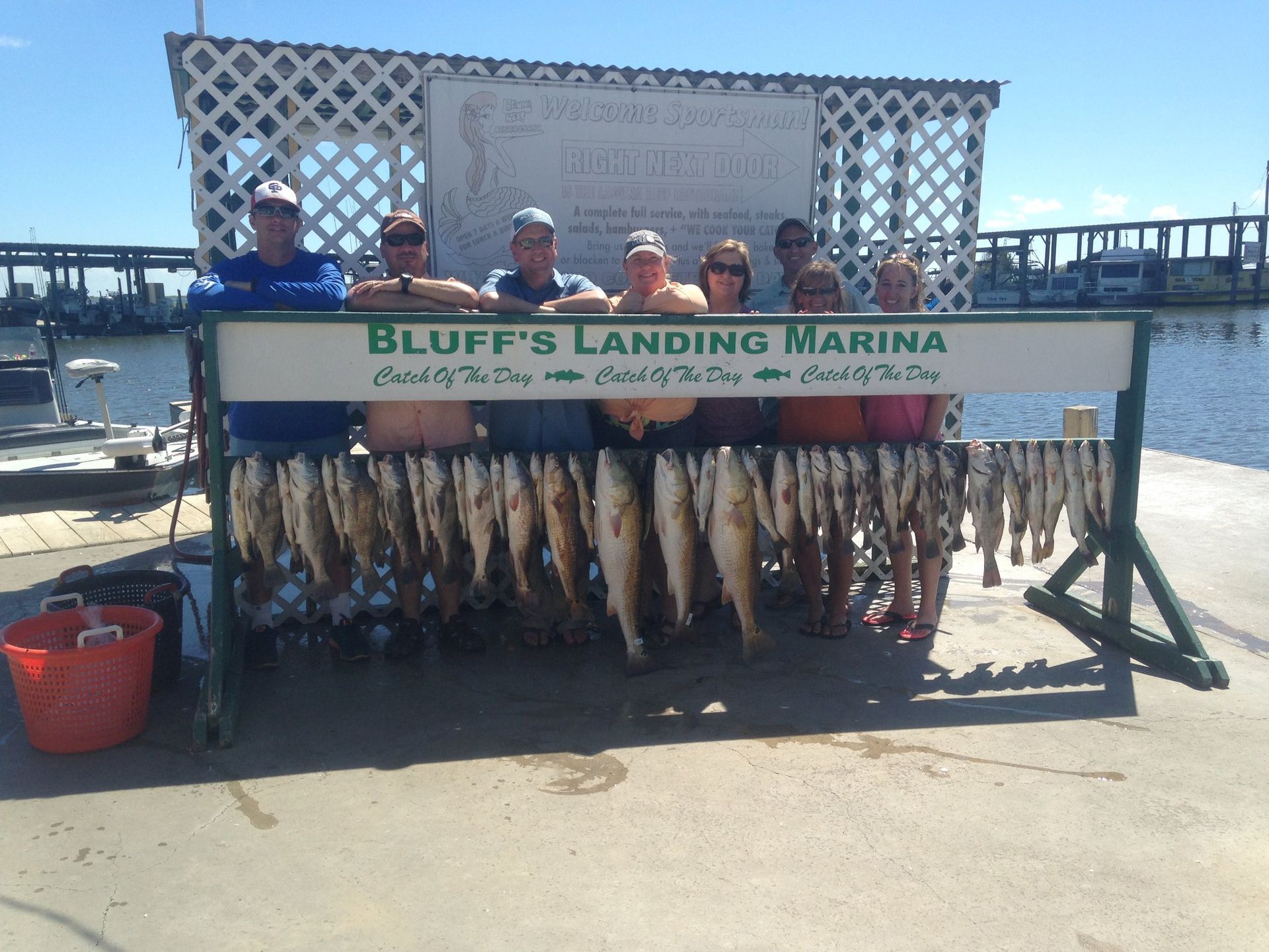 A group of people standing in front of a sign that says bluff 's landing marina