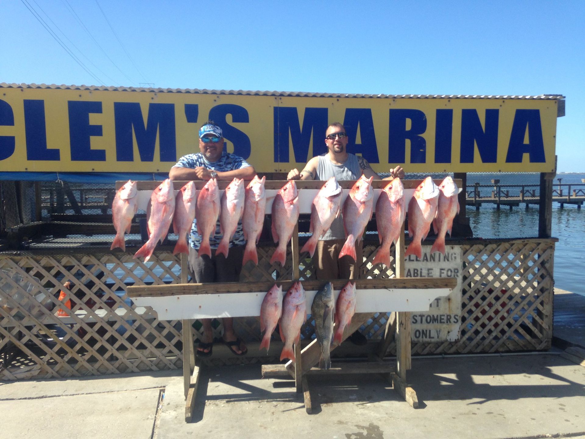 Two men standing in front of a sign that says clem 's marina