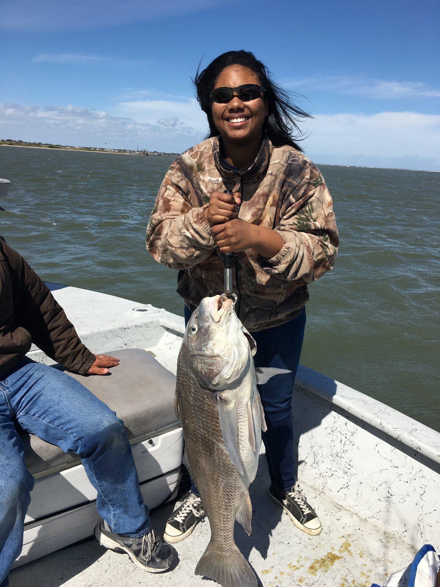 A woman is holding a large fish on a boat.