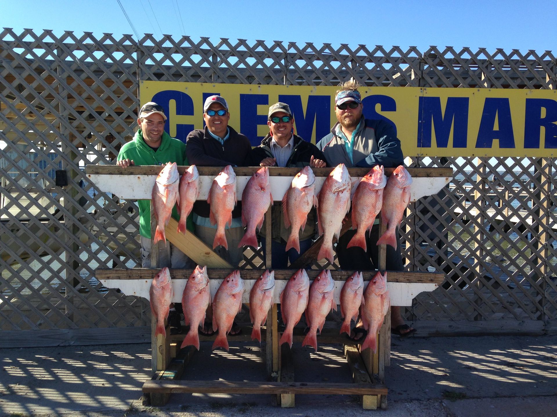 A group of men holding a bunch of fish in front of a sign that says crews mar