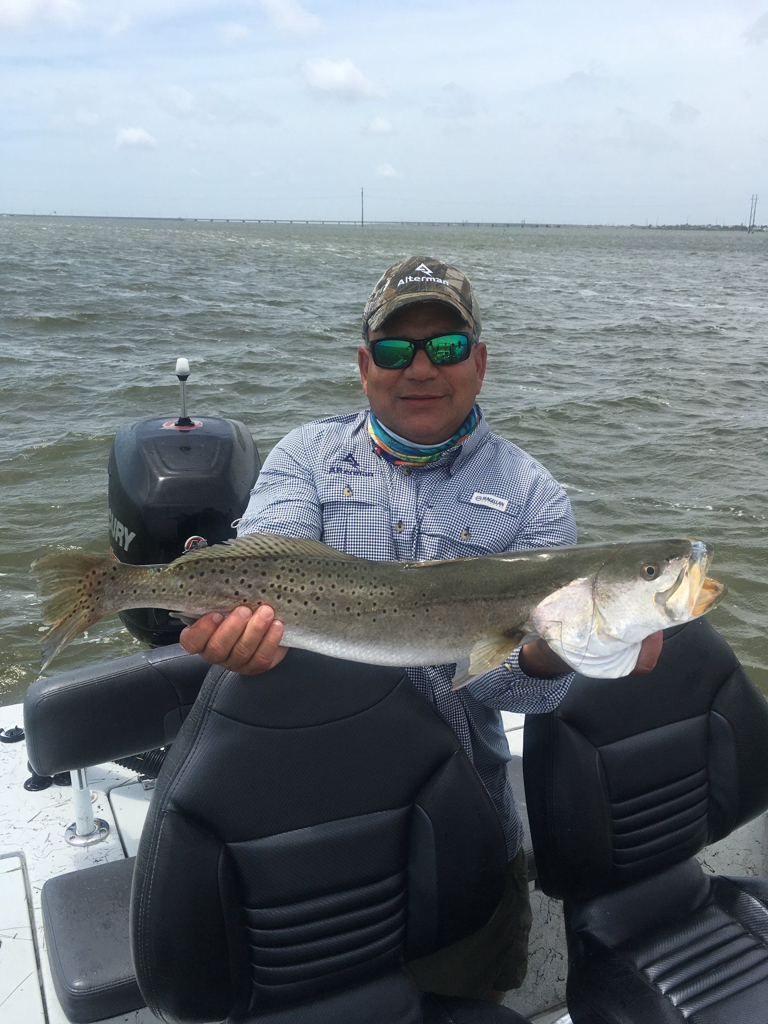 A man is sitting on a boat holding a large fish.