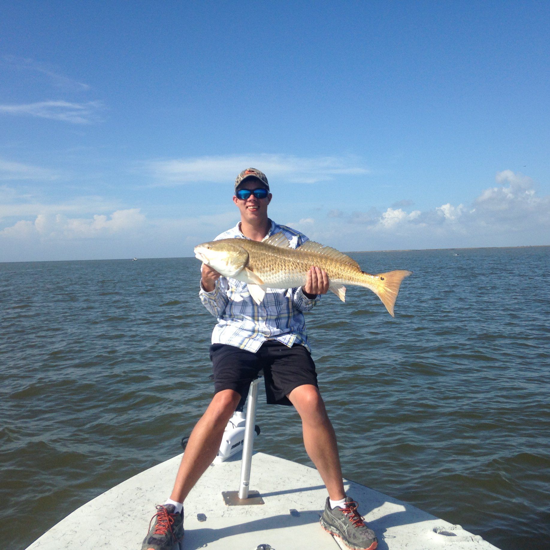 A man is sitting on a boat holding a large fish