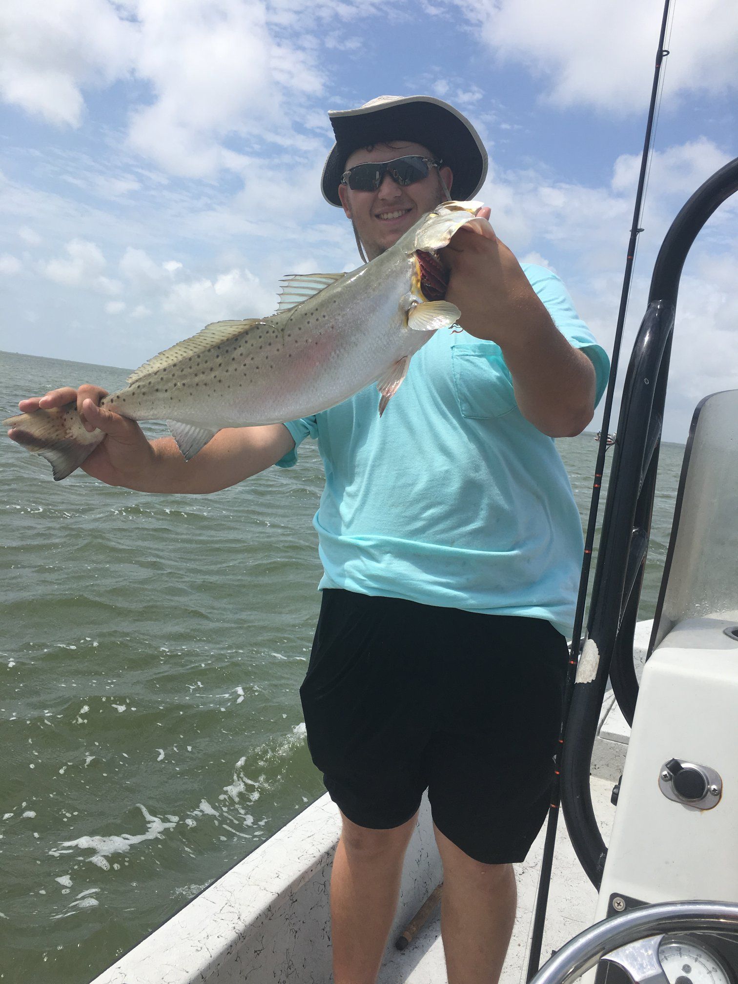 A man is standing on a boat holding a fish.