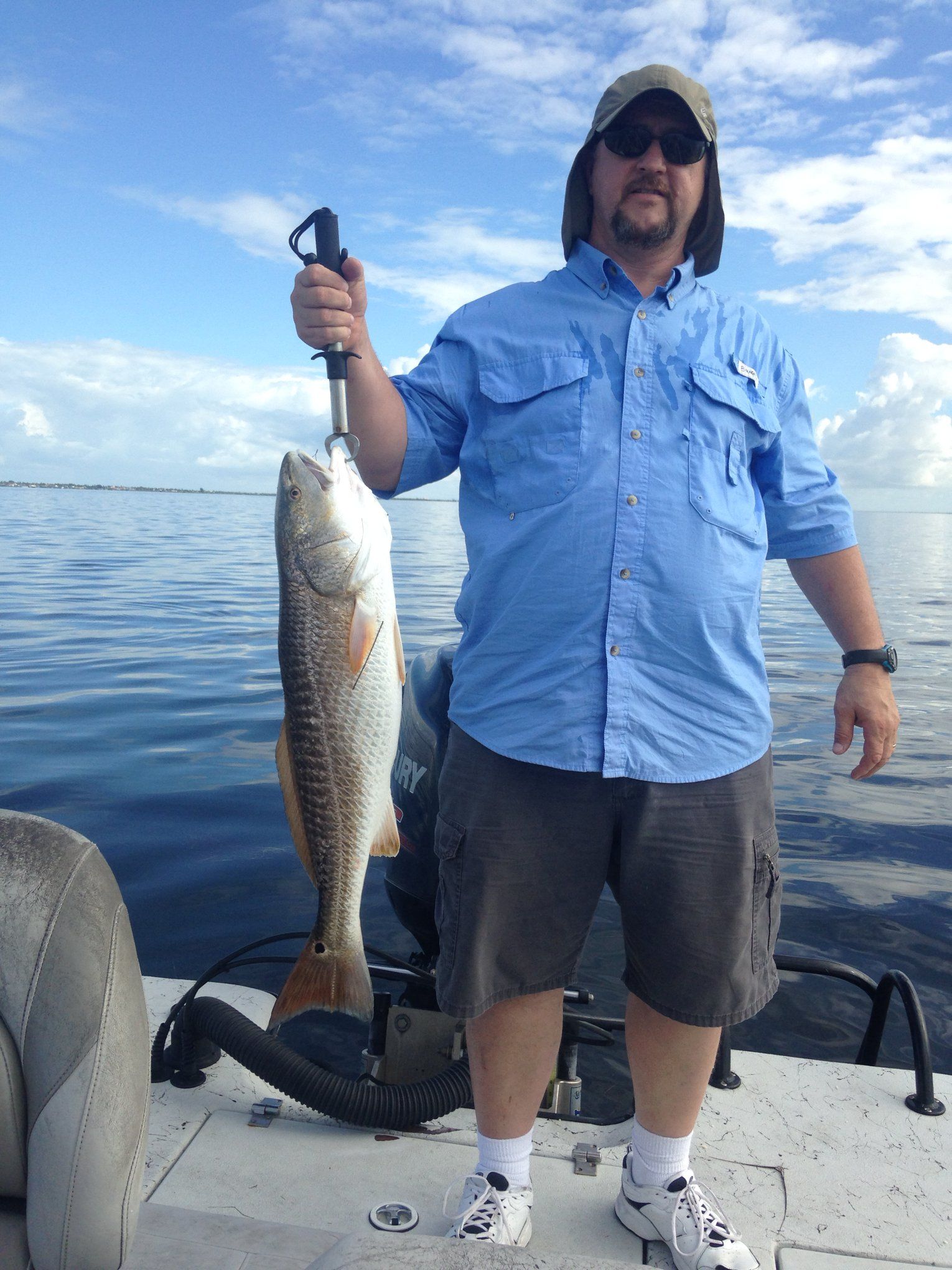 A man is holding a fish on a boat in the water.