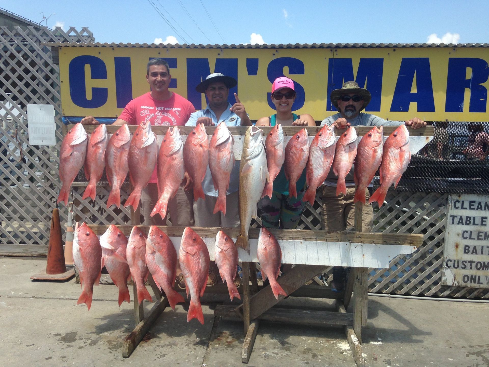 A group of people holding fish in front of a sign that says clemens mar