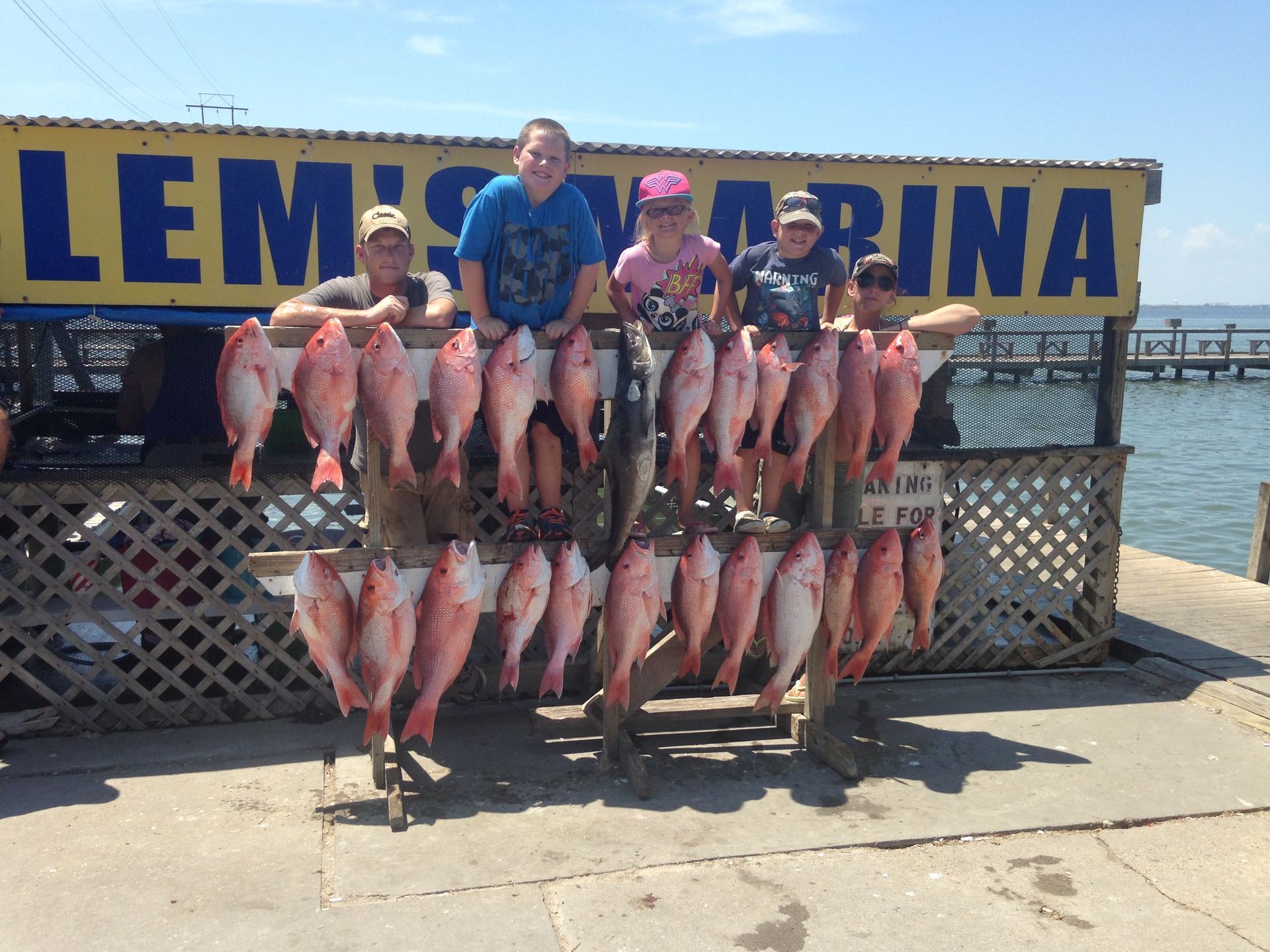 A group of people standing next to a rack of fish.