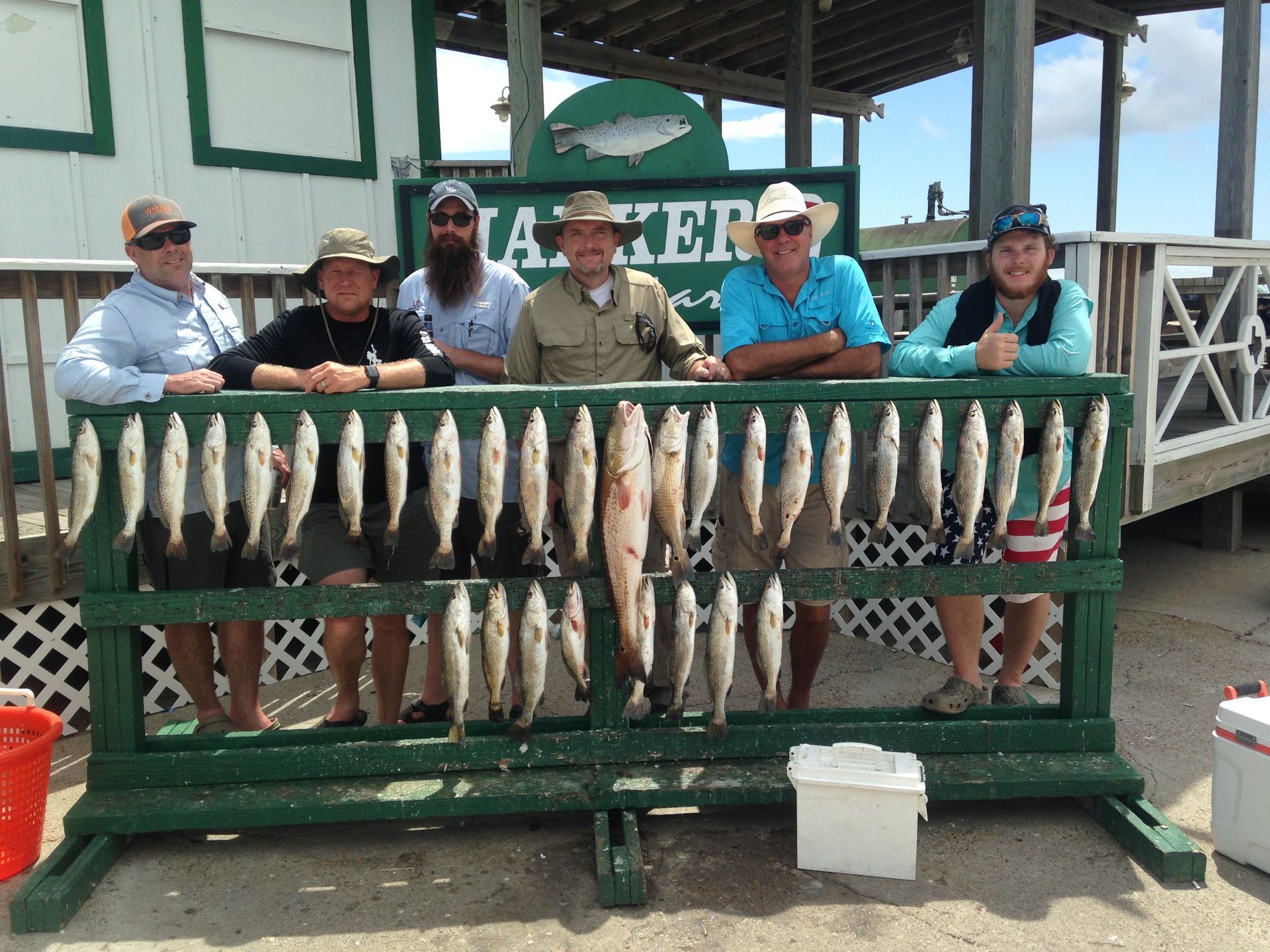 A group of people standing behind a fence with fish on it