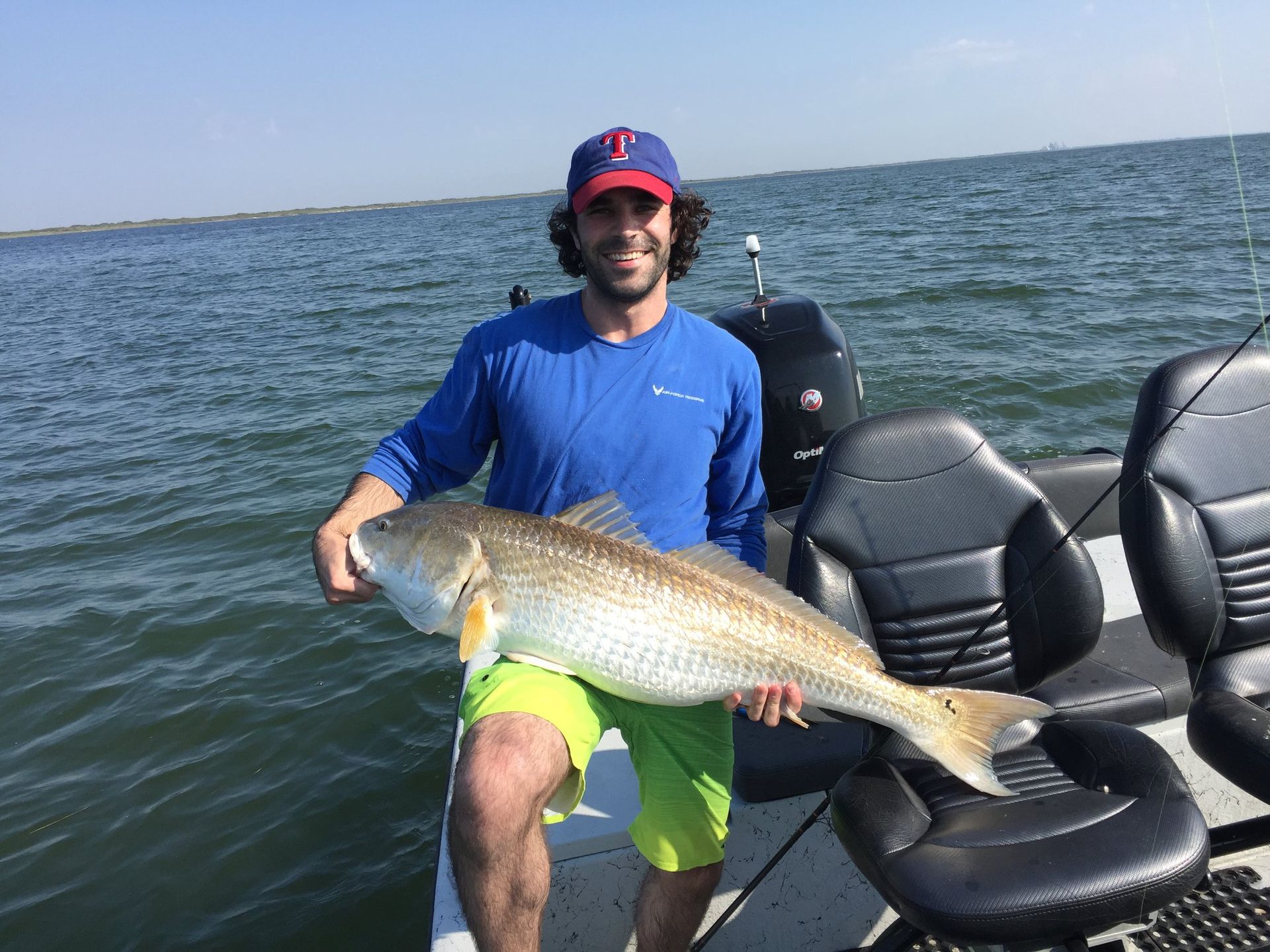 A man is sitting on a boat holding a large fish.