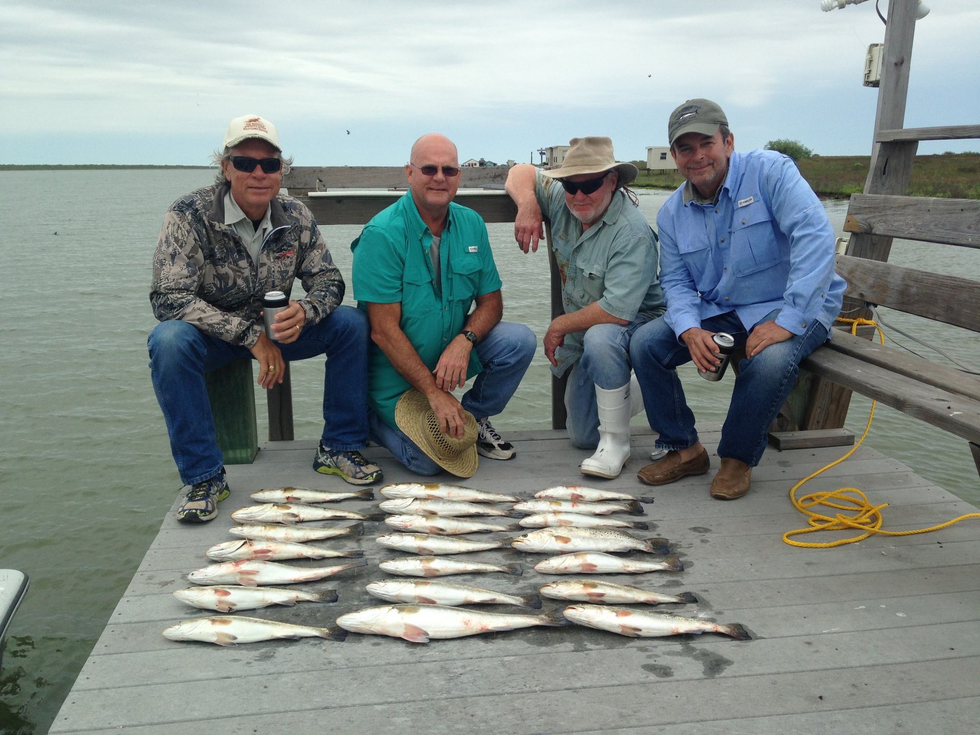 A group of men sitting on a dock with a bunch of fish