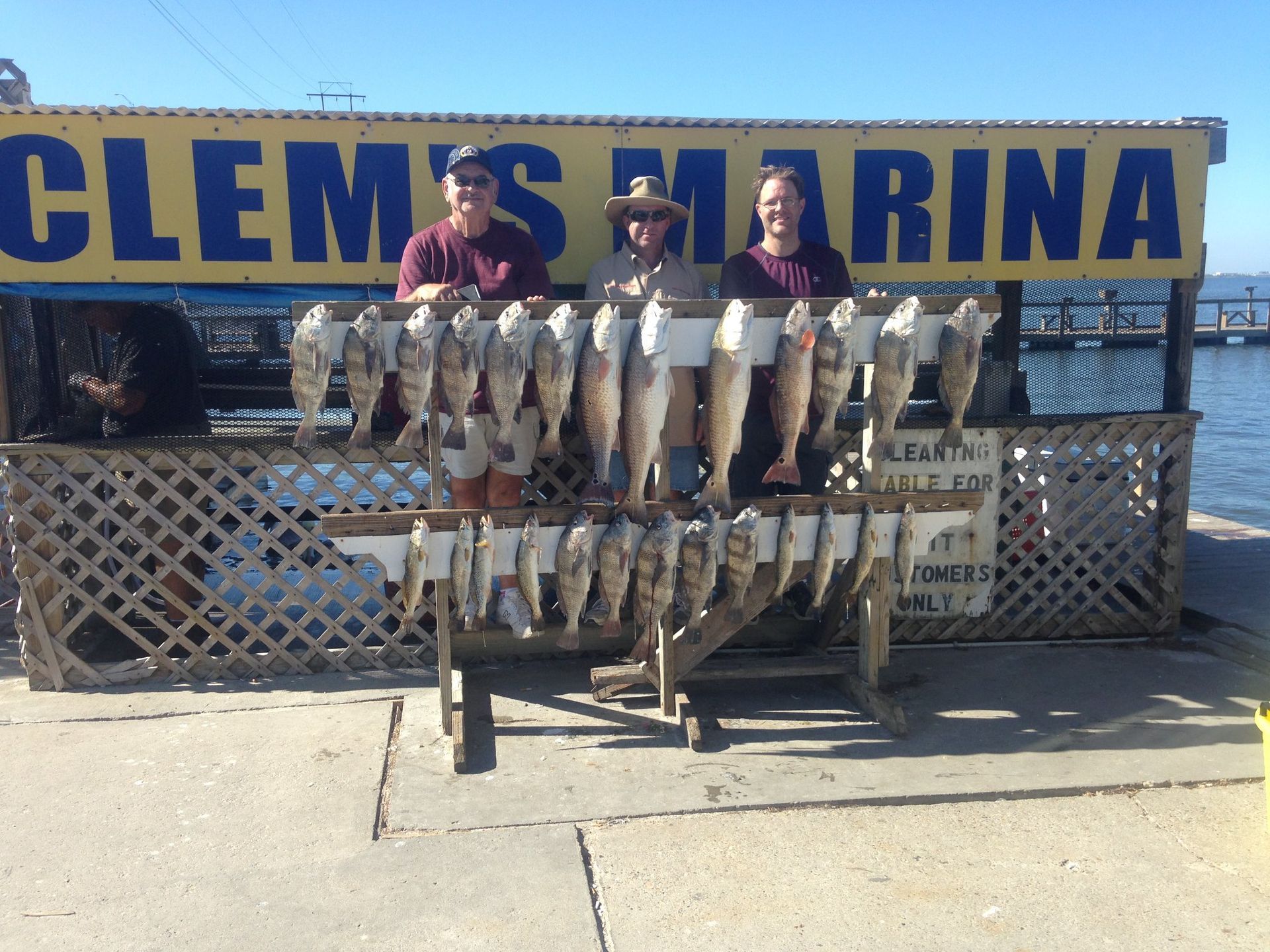 Two men standing in front of a sign that says clem 's marina