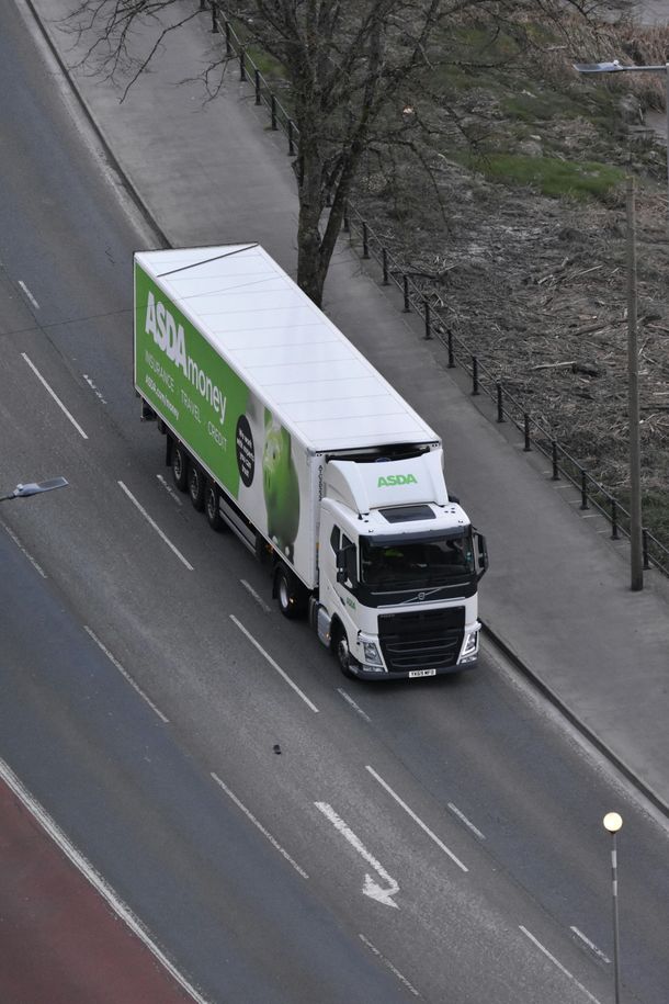 A green and white truck is driving down a road