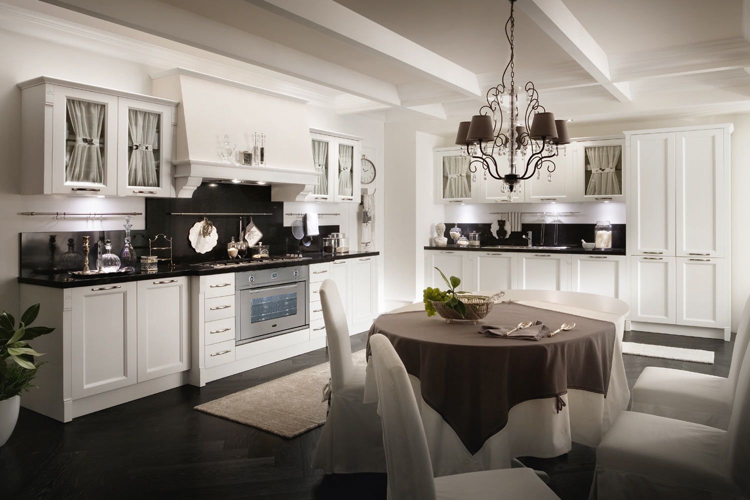 Cucina bianca con ripiani scuri, tavolo da pranzo e lampadario.