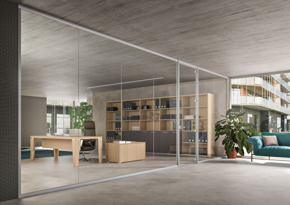 Esterno di una casa moderna con porte scorrevoli in vetro che conducono a una zona pranzo con tavolo e sedie e a un piccolo giardino con prato e un albero.