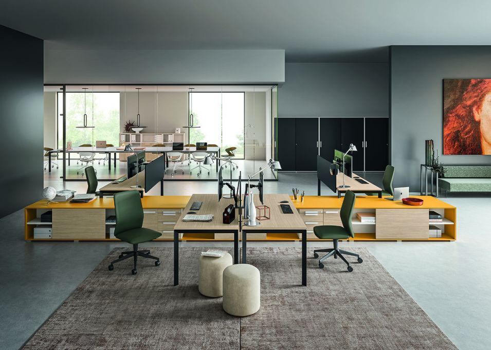 Soggiorno con divano grigio, ampie finestre e quadri raffiguranti paesaggi urbani.