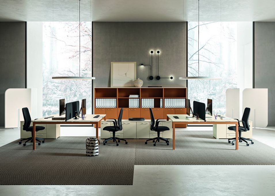 Soggiorno con divano grigio, ampie finestre e quadri raffiguranti paesaggi urbani.