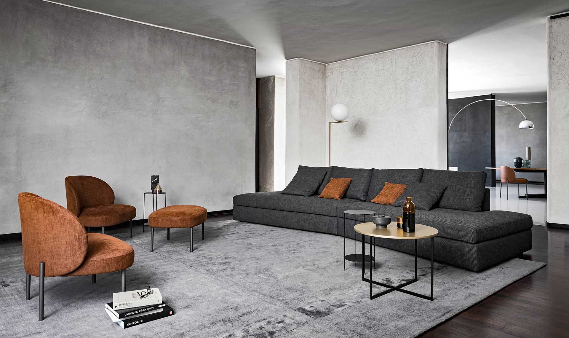 Soggiorno moderno con divano grigio, sedie arancioni e un tappeto.