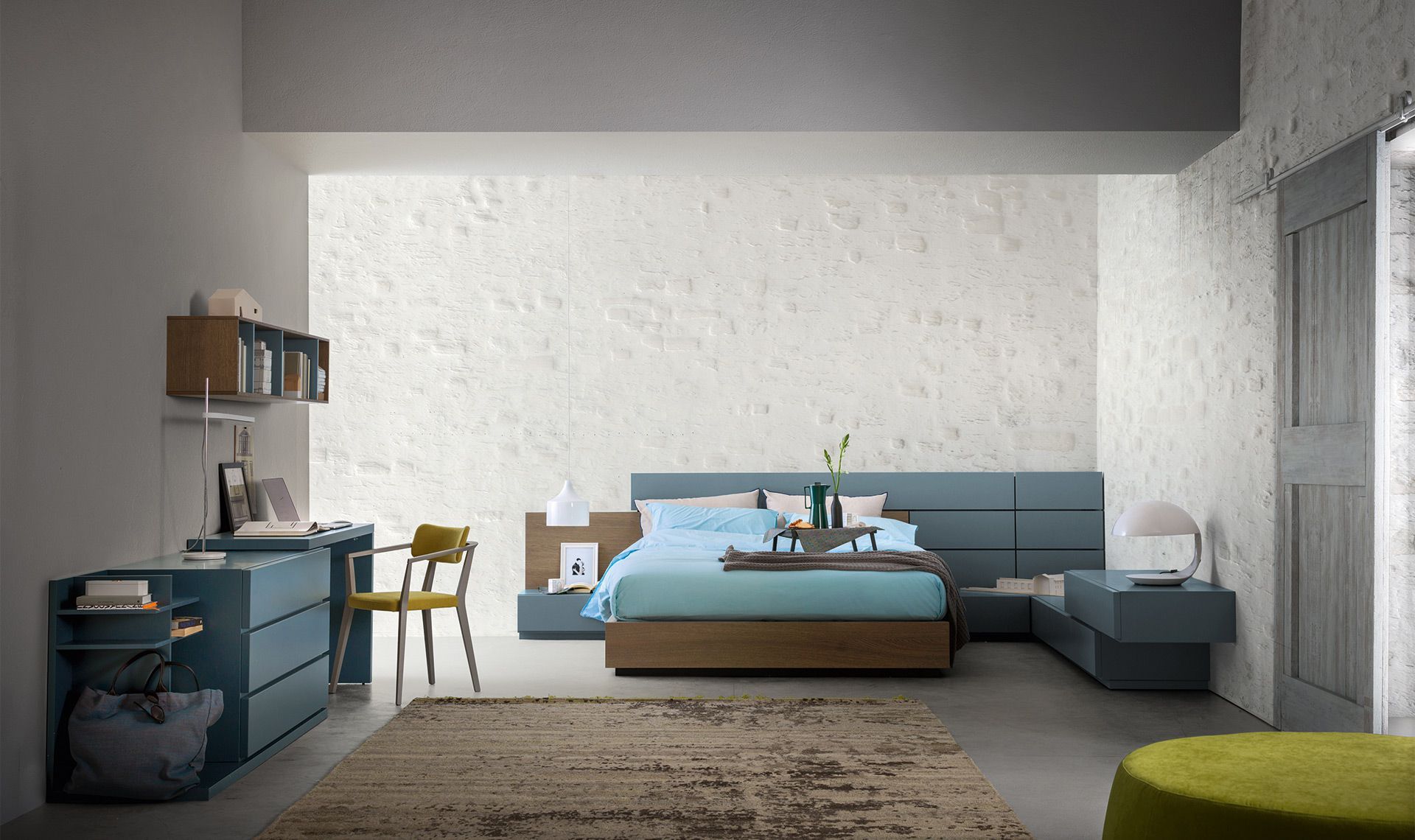 Camera da letto moderna con dettagli blu: letto, scrivania, contenitore e tappeto.