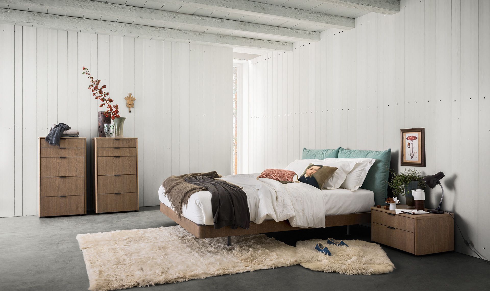 Camera da letto con mobili in legno, pareti bianche e un soffice tappeto.