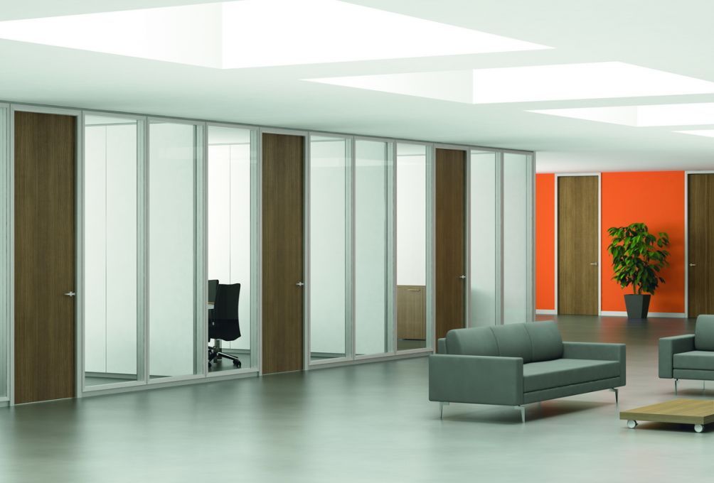 Camera da letto con letto, scrivania, scaffalatura, piante e luce naturale.