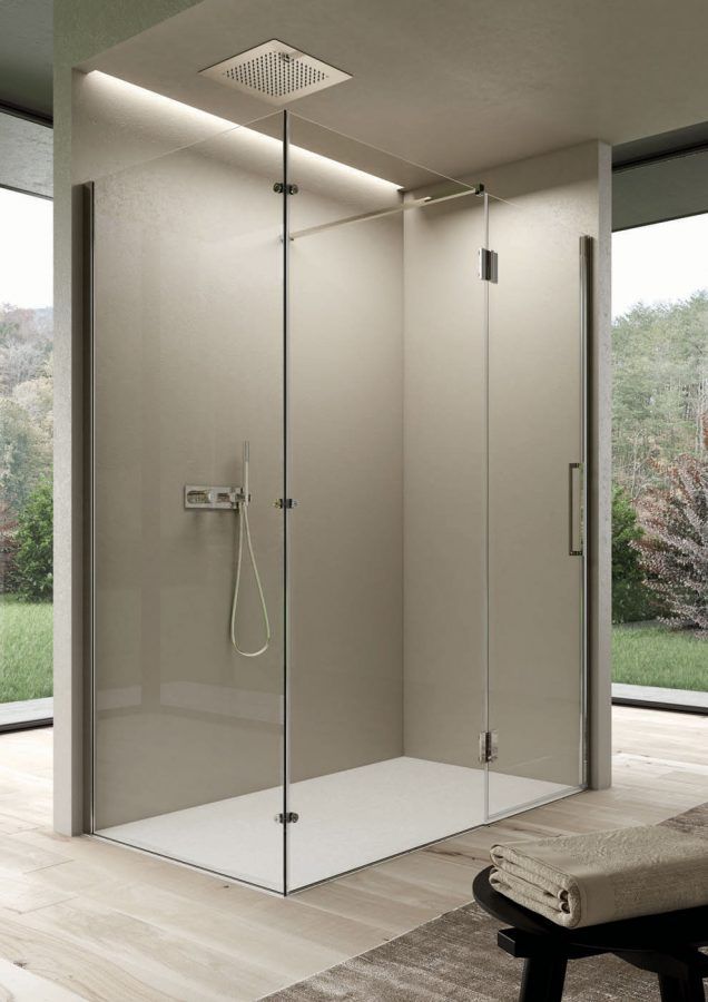 Box doccia moderno con porte in vetro, pareti neutre e base di colore chiaro, situato in una stanza con vista sull'esterno.