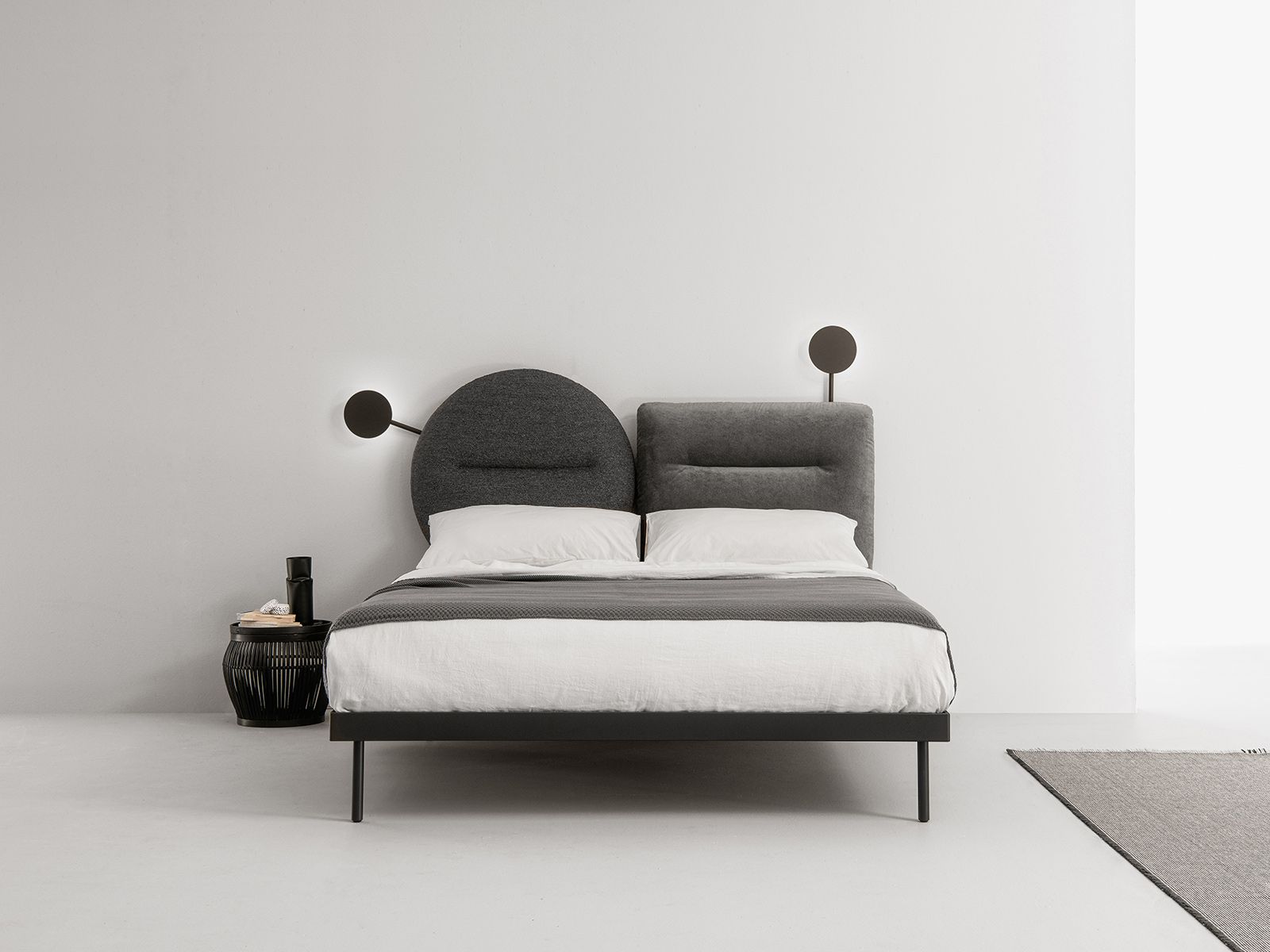 Letto moderno con testiera bicolore, struttura nera e lampade a parete.