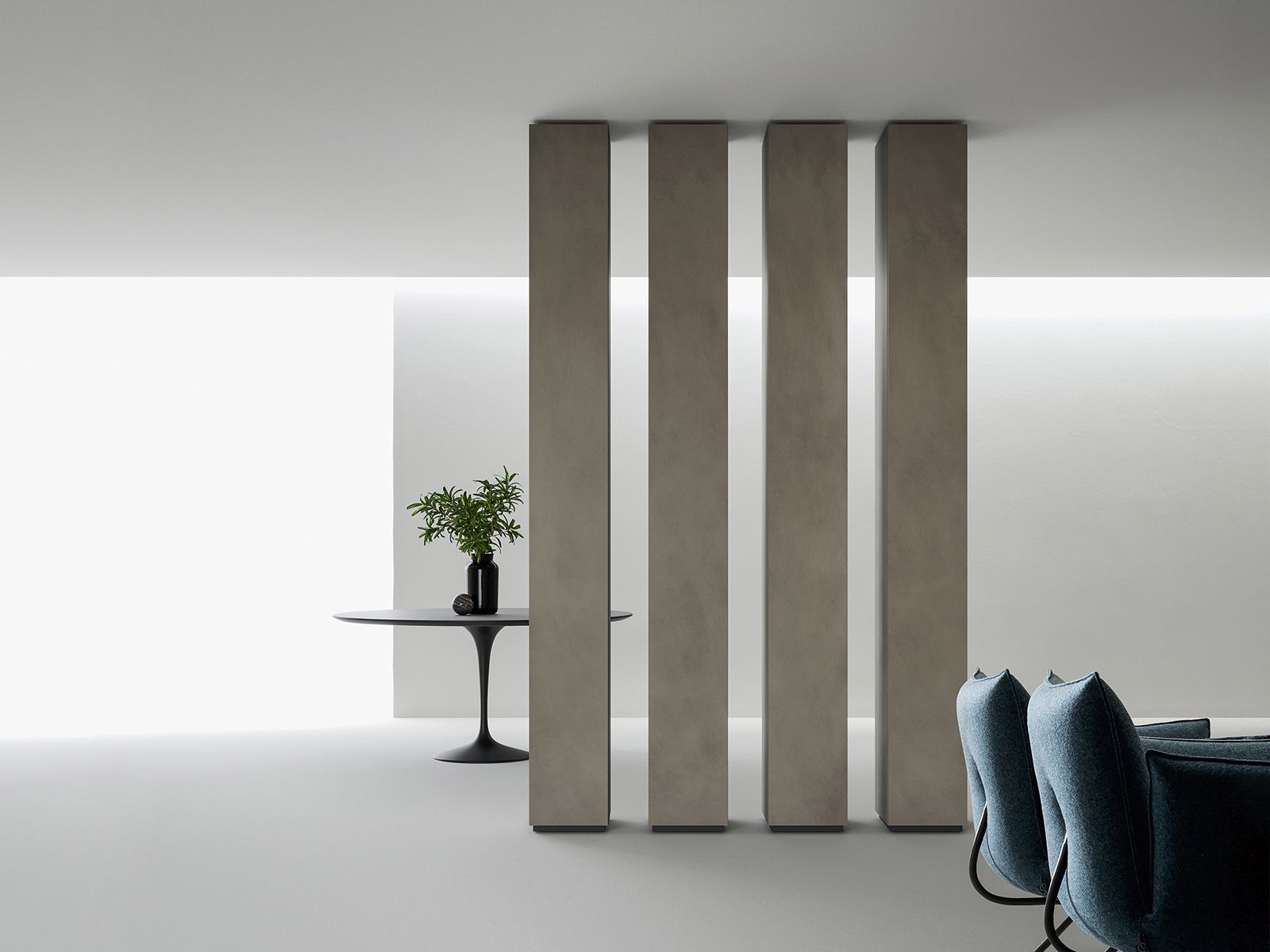 Interni moderni con divisori verticali in cemento e un tavolo rotondo con verde.