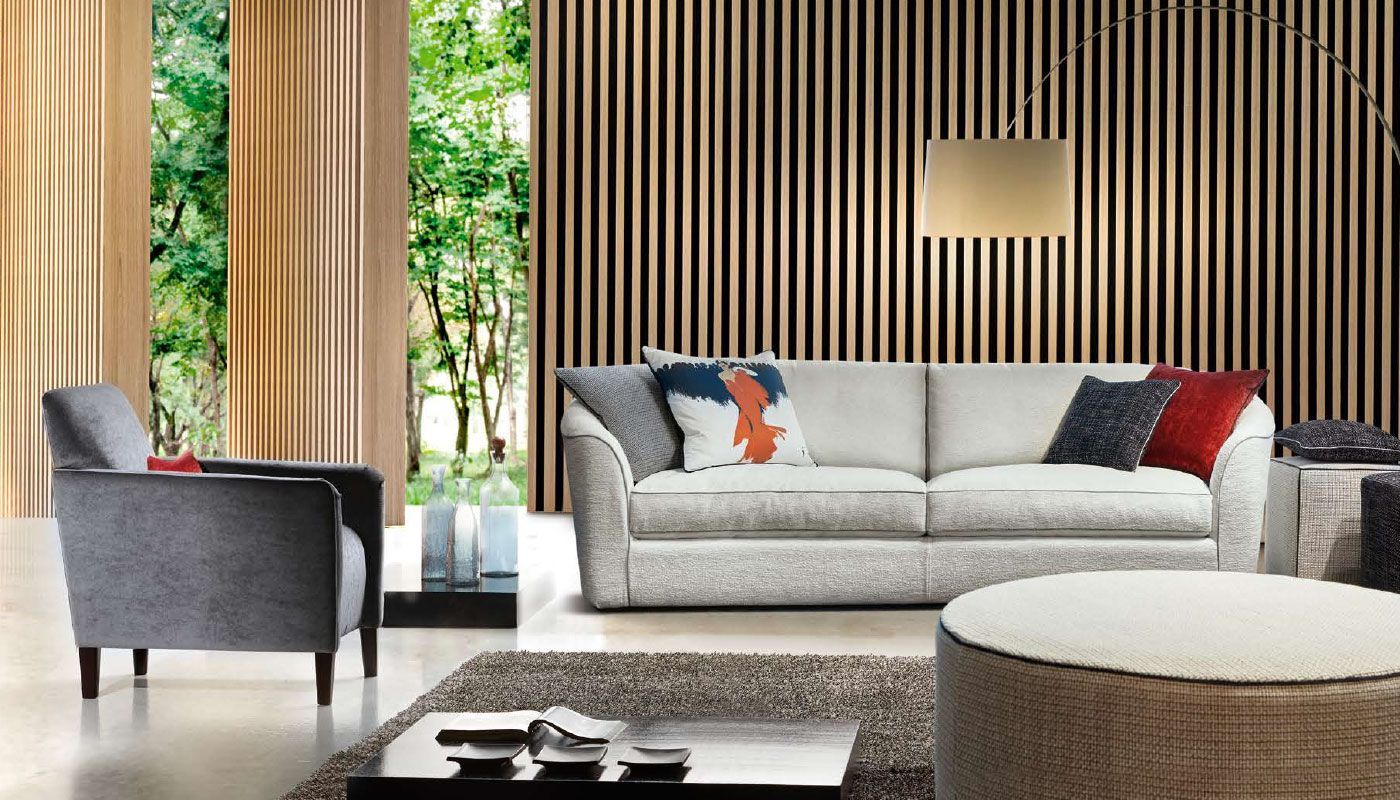 Soggiorno con divano grigio, poltrona e pouf; pareti con listelli verticali marroni e una finestra.