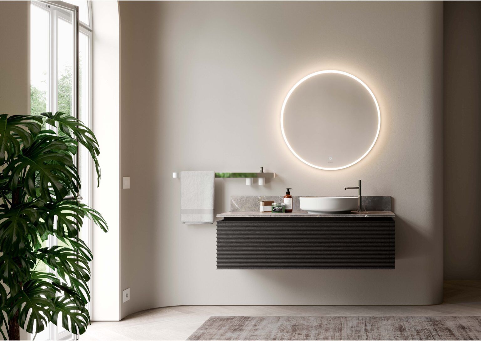 Bagno moderno con mobile lavabo sospeso, specchio circolare illuminato e grande pianta.