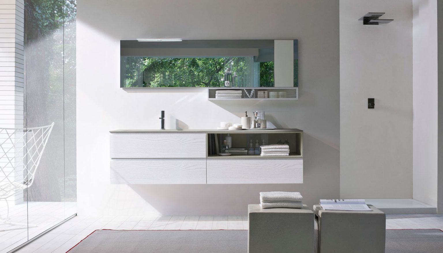 Bagno moderno con mobile lavabo sospeso bianco e grigio, grande specchio e mensola aperta con articoli da toeletta.