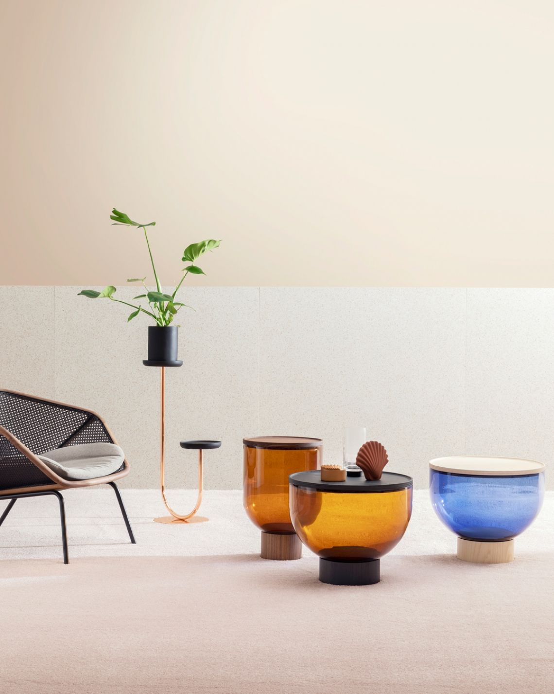 Elegante scena interna con mobili moderni: sedia, portavasi e tavoli in vetro ambra e blu su un tappeto beige.