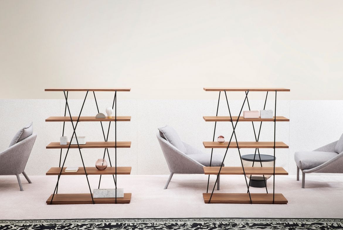 Due librerie in legno e metallo nero contro una parete chiara, con sedie e tappeto.