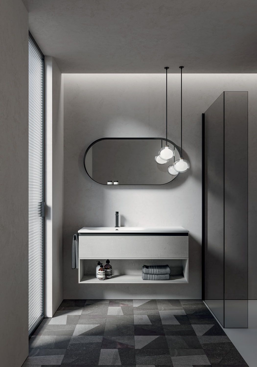 Bagno moderno con mobile lavabo grigio, specchio ovale, lampade a sospensione e pavimento decorato.