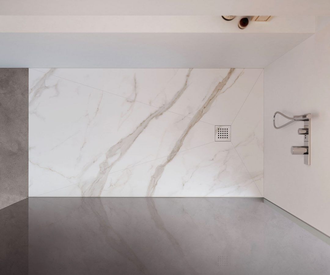 Parete doccia in marmo bianco con pavimento grigio, soffione doccia su parete bianca.